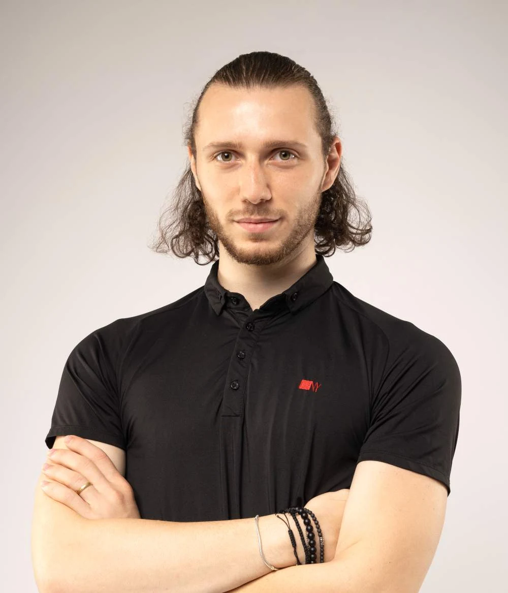 Cătălin Oțelea, în tricou negru, cu brațele încrucișate, pe fundal deschis