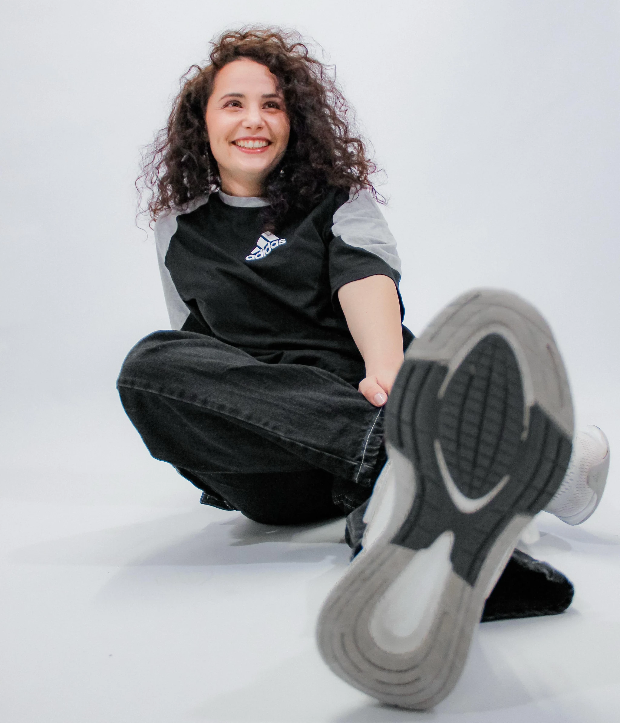 Irina Florea, în ținută neagră, așezată pe podea, zâmbind spre cameră